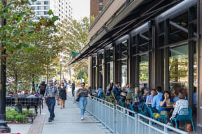 people sitting outside of a restaurant on a sidewalk