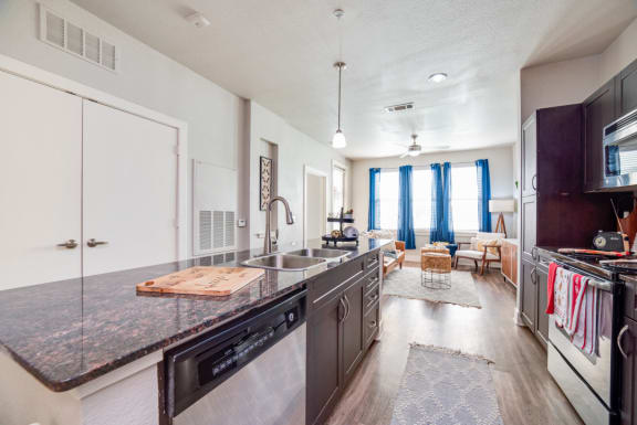 an open kitchen and living room with a large counter top and a sink at The Landings at Brooks City-Base, San Antonio, TX, 78235