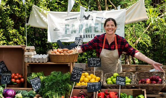 a woman standing in a market selling fruits and vegetables