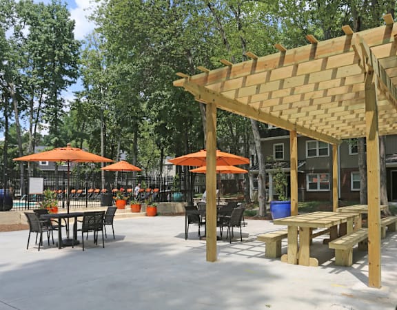 a patio with a pergola and tables with umbrellas
