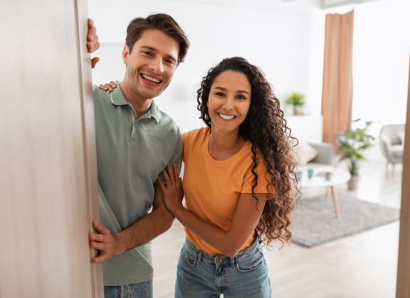 a man and woman standing behind a door in a living room