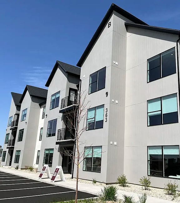 A modern apartment building with a parking lot in front.