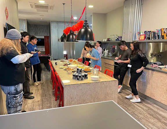 A group of people are gathered around a table in a kitchen.