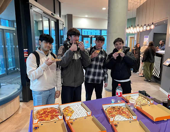 Four people eating pizza in a room.