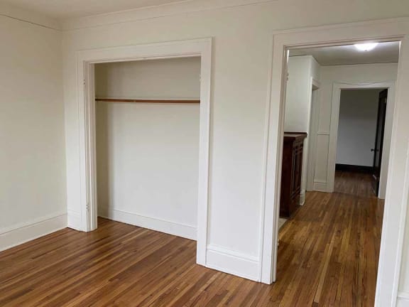 a bedroom with white walls and hardwood floors