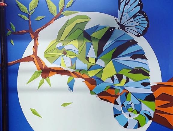 A Chameleon and butterfly on a branch over the moon on a wall mural at Citizen Birmingham