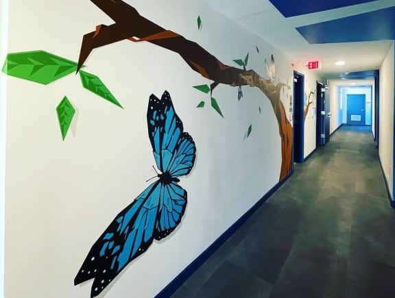 a residential hallway with a butterfly and tree mural on the wall at The Citizen Birmingham