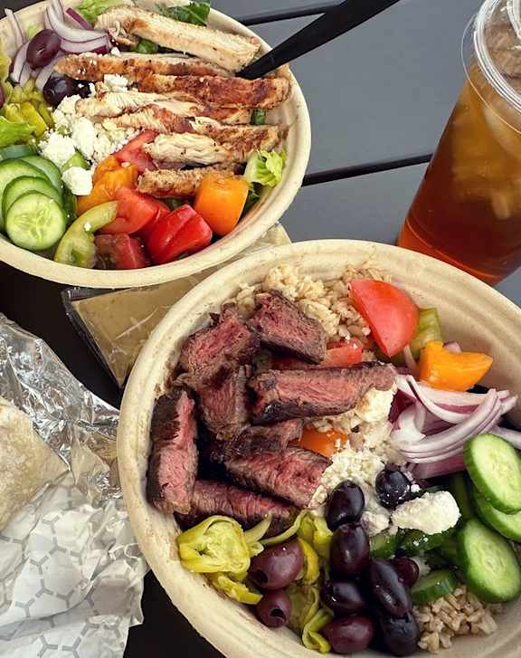 A meal consisting of a wrap, a salad, and a bowl of grilled meat and vegetables.