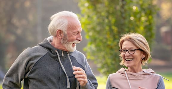 An older couple jogging in a park.