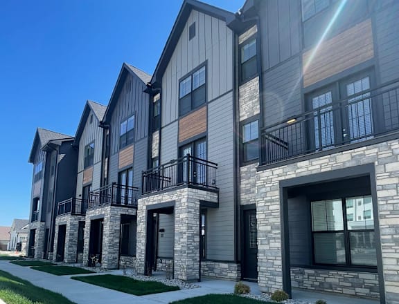 a row of townhouses with stone and wood exterior on a sunny day at Fishers District, Fishers, IN