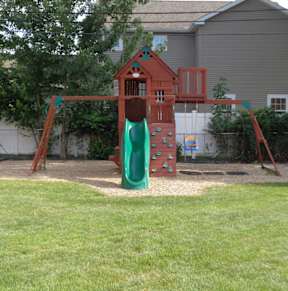 A playground with a green slide and a red swing set.
