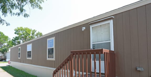 a brown and white mobile home with a wooden deck
