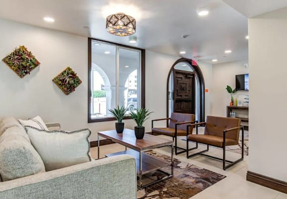 A living room with a grey couch, a coffee table, and a large arched doorway.