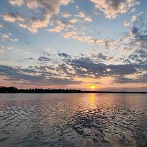 a sunset over a body of water with clouds in the sky