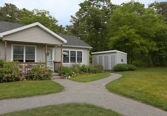 A house with a grey roof and a small shed in the backyard.