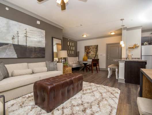 A living room with a white couch and a brown ottoman.