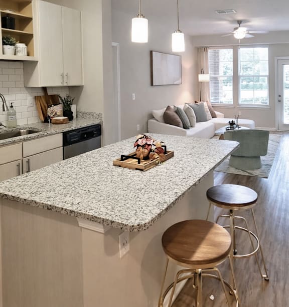 A kitchen with a granite countertop and bar stools. at TRAILSIDE VERDAE Apartments , GREENVILLE, South Carolina