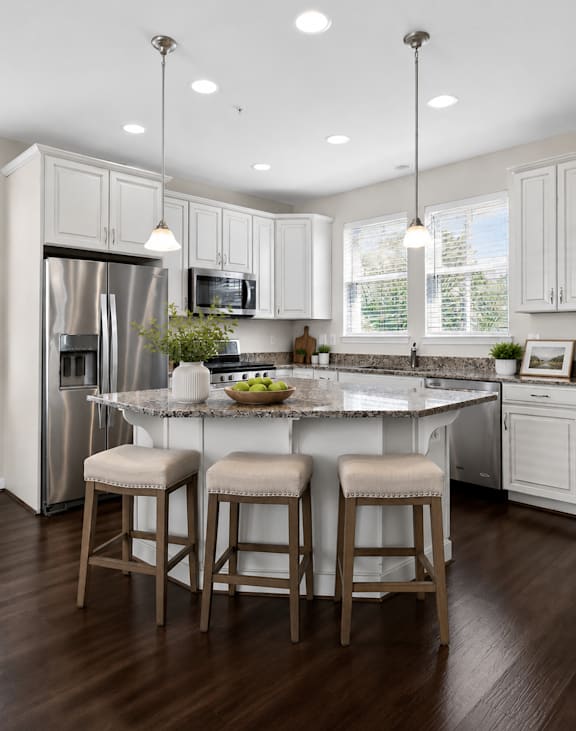 A kitchen with white cabinets and a wooden floor.