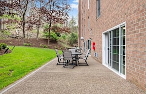 A patio with a table and chairs is in front of a brick building.
