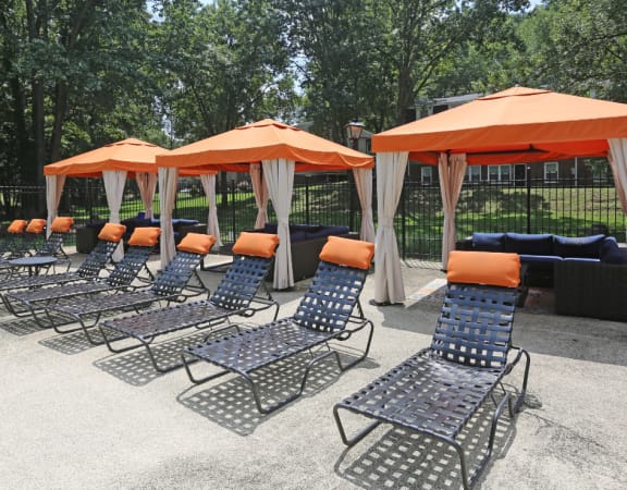 a row of chaise lounge chairs with orange umbrellas
