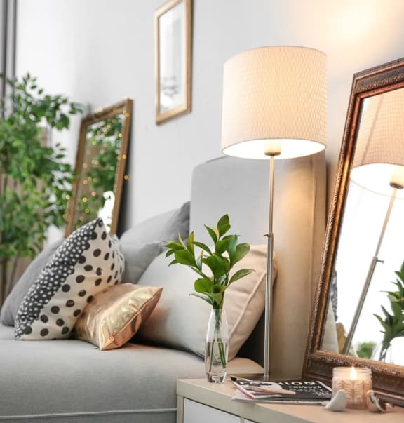 a living room with a couch and a table with a vase with a plant on it