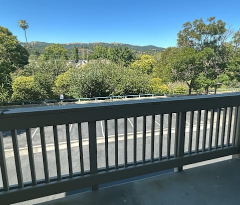A balcony with a railing overlooking a road and trees.