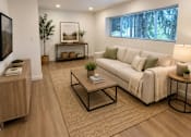 Thumbnail 4 of 8 - A modern living room with a white sofa, wooden coffee table, and a large window.
