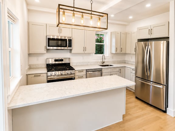 A modern kitchen with a stainless steel refrigerator and a white island.