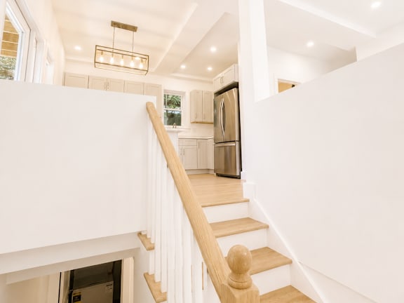 A white staircase with a light brown handrail.