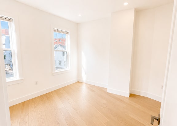 A room with wooden flooring and white walls.