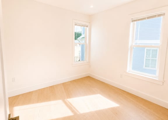 A room with wooden floors and two windows.