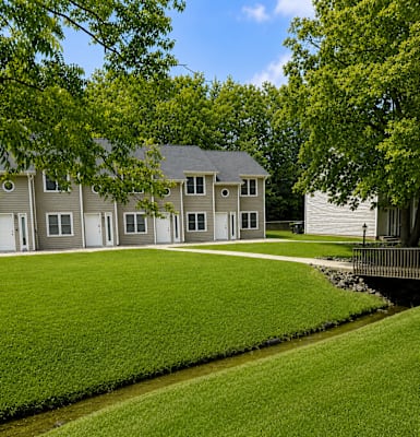 A house with a green lawn and a small stream running in front of it.