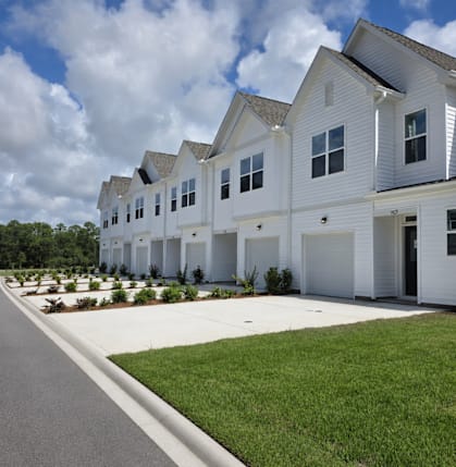 A row of white houses with green lawns in front.