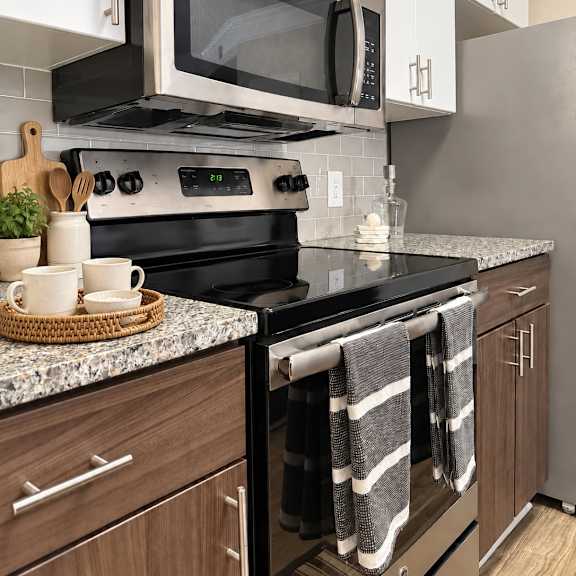 A modern kitchen with a black stove top oven and a black microwave above it.