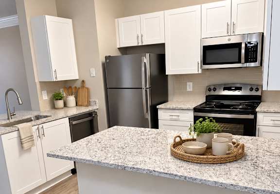 A kitchen with a granite countertop and stainless steel appliances.