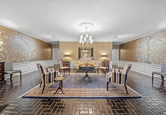A dining room with a large table surrounded by chairs.