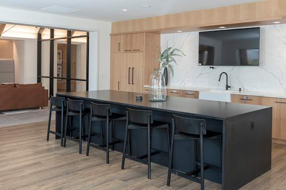 A kitchen with a black countertop and bar stools.