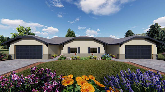 A modern house with a large front yard and colorful flowers.