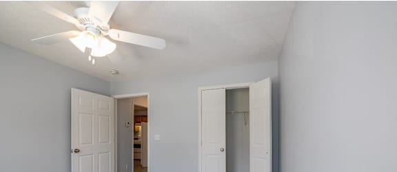 a bedroom with a ceiling fan and a door to a bathroom