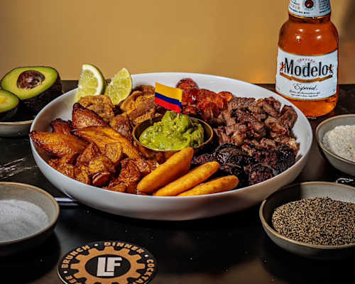 A bottle of Modelo beer is next to a bowl of food.