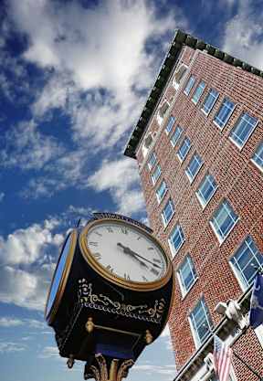 a clock on a pole in front of a brick building