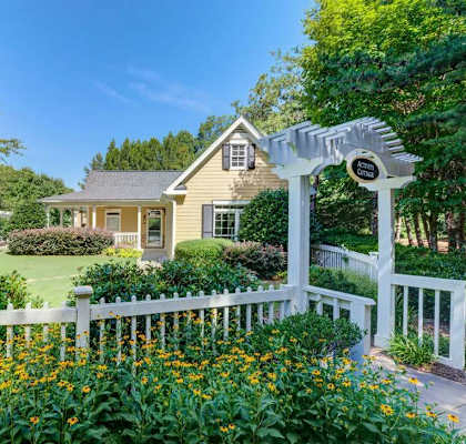 A house with a white fence and a white archway with a sign on it.