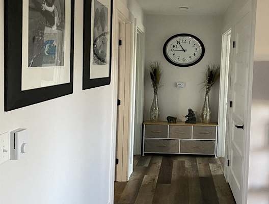 a hallway with a clock on the wall and a dresser