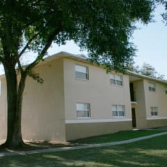 the exterior of an apartment building with a sidewalk and trees