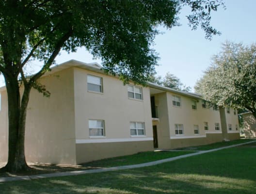 the exterior of an apartment building with a sidewalk and trees