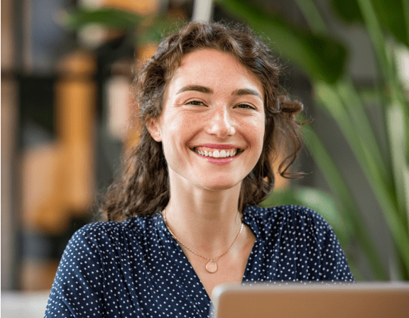 a woman smiling while looking at a laptop computer