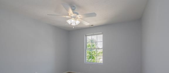 an empty room with a ceiling fan and a window
