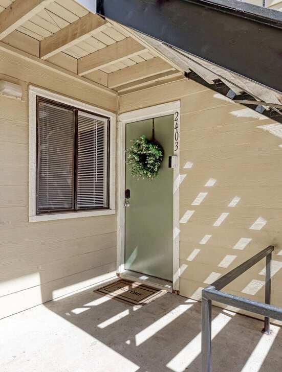 A staircase with a metal railing and a green door.