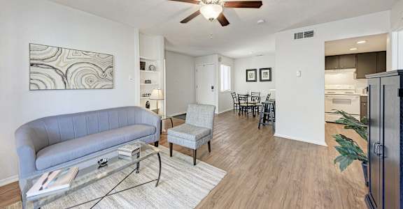 A living room with a grey couch and a glass coffee table.