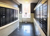 Thumbnail 15 of 23 - A long hallway with a row of mailboxes on either side.